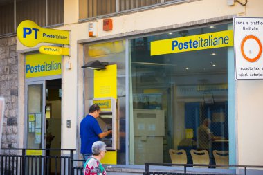 Castelmola, SICILY, ITALY - SEPTEMBER 28, 2019: An elderly man takes money in postamat  in Posteitalian in the tourist old town of Castelmola