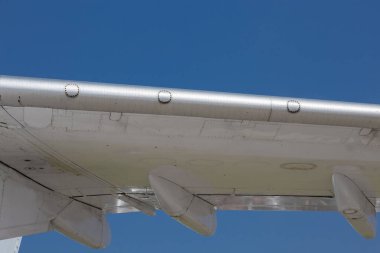Wing of an old airplane against a blue sky on a Sunny day with rivets and bolts, abstract technological background