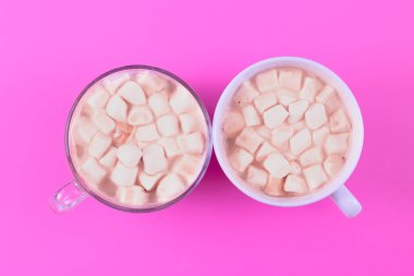 Two Hot cocoa in a glass mug with marshmallow on a colored background in the middle