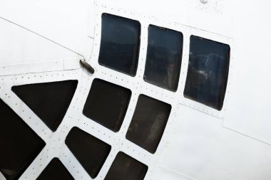 Uçak gövdesinde pencere delikleri, perçin ve güneş tarafından aydınlatılan cıvatalarla gövdenin bir parçası.