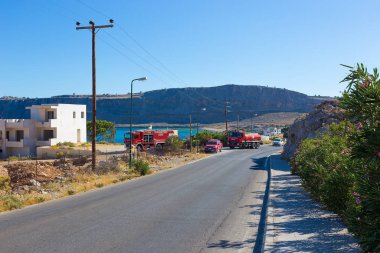 RHODES, GREECE - JULY 12, 2019: Firefighters came to the fire of dry grass in the mountains near the highway near the city of Lindos on the island of Rhodes in Greece, a fire truck is on the road.