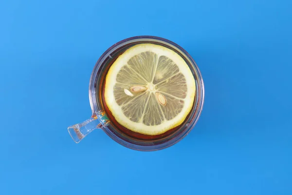 Cup of Hot tea with lemon in a ceramic mug on a colored blue background