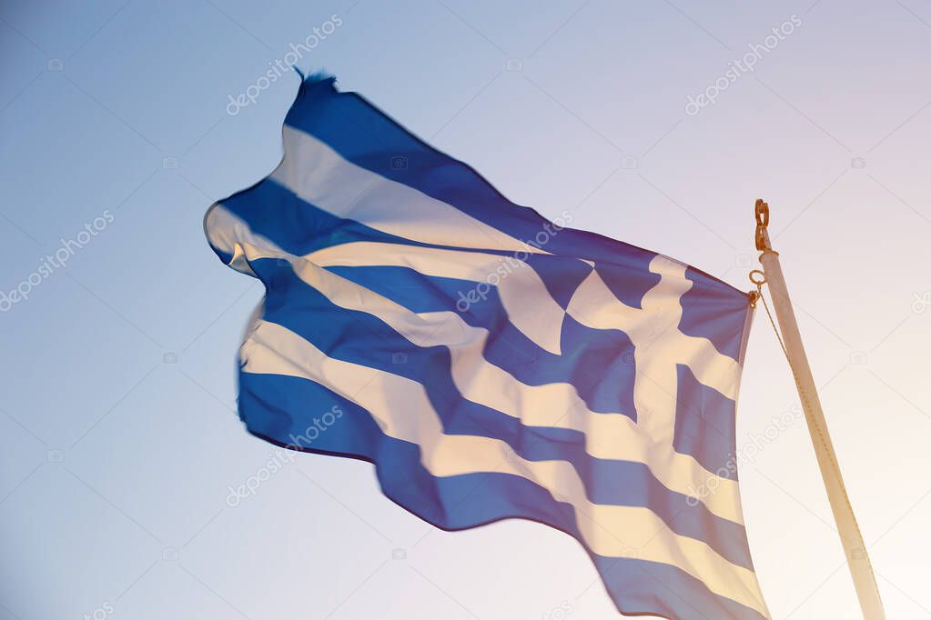 waving Greek flag against the sky at dawn or sunset