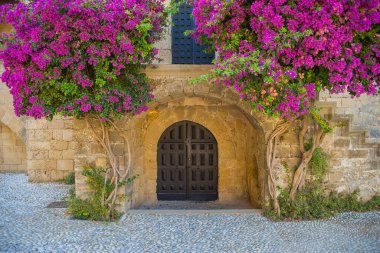 Merdivenlerin yanındaki çiçekli bougainvillea, Yunanistan 'ın Rodos adasındaki eski şehrin eski kalesi ve caddeleri. Gündüz vakti adanın cazibesi.