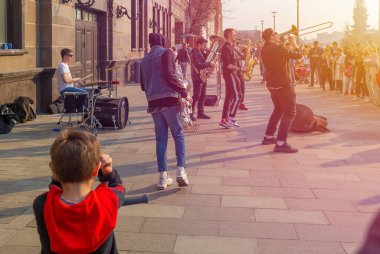 Moskova, Rusya - 21 Nisan 2019: Sokak müzisyenleri, güneşli bir bahar gününde Yakimanskaya setinde seyircilerin ve turistlerin önünde gösteri yaptılar. Patrik köprüsü yakınlarında çeşitli müzik aletleri çalan bir erkek grubu var.