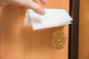 Kapıdaki peçete virüse karşı korunmak için günlük hayatta ve insan hayatında mikropların ve virüslerin yayıldığı bir evde veya bir dairede kapı kolunun tutulduğu şeyler ve objeler.