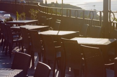 İtalya 'nın Sicilya kentindeki Taormina şehrindeki meydanda ve gözlem güvertesinde ziyaretçileri olmayan boş bir restoranda siyah plastik sandalyeler ve masalar.
