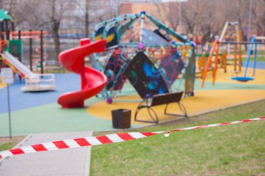 Parkın yakınındaki oyun parkında kırmızı ve beyaz kısıtlayıcı bant, Moskova 'da koronavirüs salgını tehdidi nedeniyle sokaktaki oyun alanını ziyaret etme yasağı