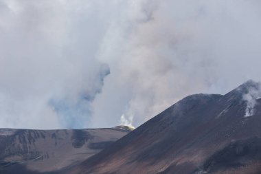 Etna volkanı, İtalya 'nın Sicilya bölgesinde bulutlara ve gökyüzüne beyaz duman ve gri kül püskürtür.