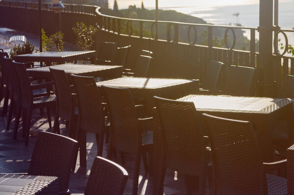 Black plastic chairs and tables in an open empty restaurant without visitors on the square and observation deck in the city of Taormina in Sicily in Italy