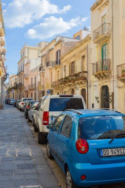 Syracuse, SICILY, ITALY - 2 Ekim 2019: Güneşli bir günde Sicilya 'nın Syracuse şehrinde dar bir caddede bir otoparkta mavi matiz