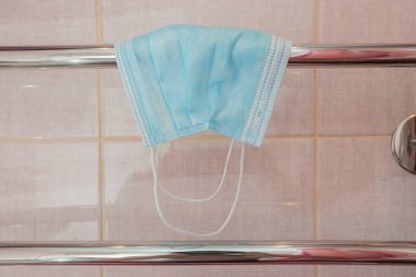Antiviral maske banyodaki havlu askısında kurumuş.