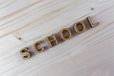 Tahta arka planda kontrplak lazer kesiminden kalma yazıt okulu.