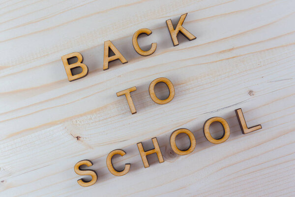 The inscription back to school from plywood laser-cut on wood background