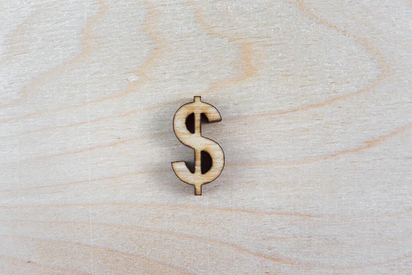 Dollar sign of plywood laser cut on a wooden background