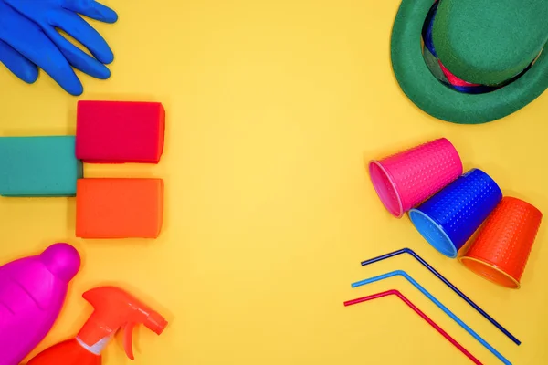 Mise en page des outils de nettoyage. Chapeaux multicolores, gobelets en plastique et pailles pour cocktails sur fond jaune. Service de nettoyage après les fêtes et événements festifs — Photo