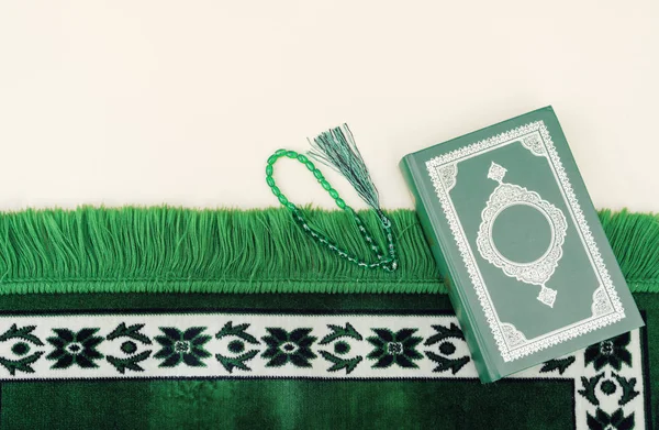 Μουσουλμανική ισλαμική πίστη έννοια Κοράνι βιβλίο, πράσινο κομπολόι, πράσινο χαλί προσεύχονται. Ουδέτερο μπεζ φόντο. διάταξη και χώρος για κείμενο — Φωτογραφία Αρχείου