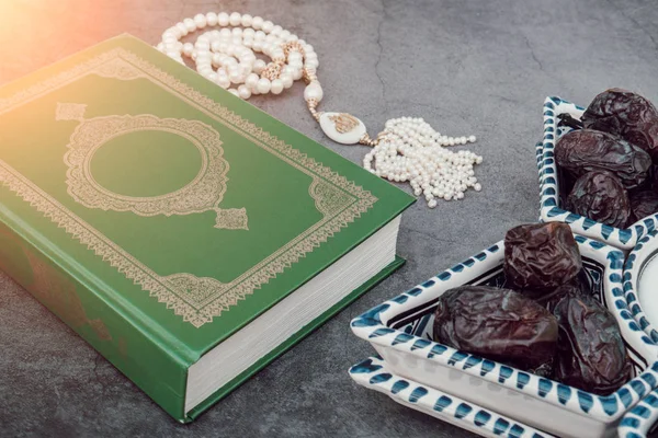 Koranbuch des muslimischen islamischen Glaubens, weißer Rosenkranz mit der Inschrift Allah, Jahreszahl in der Schale im arabischen Stil. grauer dunkler Betonhintergrund. Layout und Platz für Text. Die Sonne scheint — Stockfoto