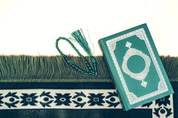Muslim islamic faith concept Koran book , green rosary, green mat pray . Neutral beige background. layout and Space for text