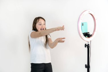 Genç bir kız dans ediyor ve video çekiyor. Selfieler. Telefon bir tripoda monte edilir ve yüzük lambası parlar.