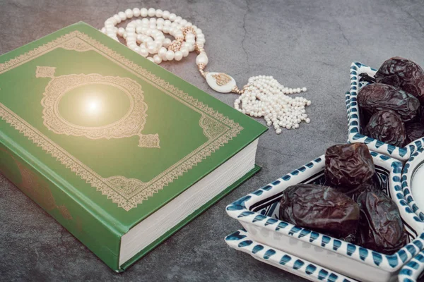 Koranbuch des muslimischen islamischen Glaubens, weißer Rosenkranz mit der Inschrift Allah, Jahreszahl in der Schale im arabischen Stil. grauer dunkler Betonhintergrund. Layout und Platz für Text. Die Sonne scheint — Stockfoto