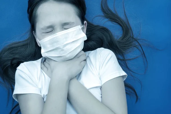 Дівчина-підліток у масці тримає горло. Їй дуже боляче. Тонована фотографія . — стокове фото