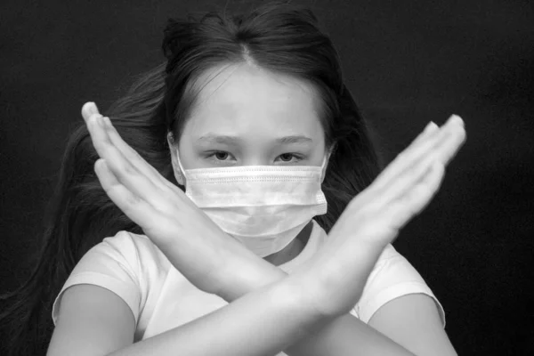 Chica adolescente en una máscara muestra una protesta con sus manos. Detener el coronovirus y la epidemia de gripe. Foto en blanco y negro — Foto de Stock