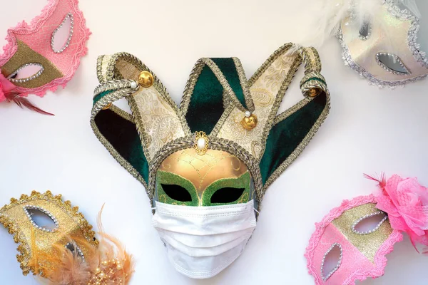 Classic venetian carnival mask in a medical protective mask against the white background of the flag of Italy. The concept of the spread of coronavirus in Italy
