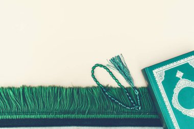 Müslüman İslam inancı kavramı Kuran kitabı, yeşil tespih, yeşil minder duası. Tarafsız bej arka plan. Metin için düzen ve boşluk.