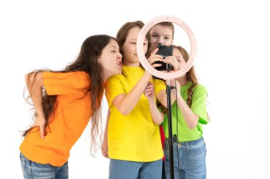 Üç genç kız ve bir oğlan gülümsüyor ve bir video çekiyor. Selfieler. Telefon bir tripoda monte edilir ve halka lambası parlar. Negatif duygular ve sosyal ağlar..