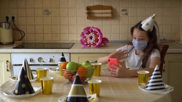 Uma Menina Boné Festivo Uma Máscara Médica Senta Mesa Sozinha — Vídeo de Stock