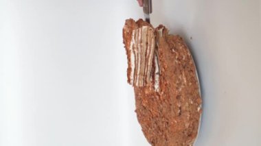 El yapımı ballı kek. Dikey çekim. Bıçaklı bir el bir parça kek kaldırır ve onu bir bölümde gösterir..