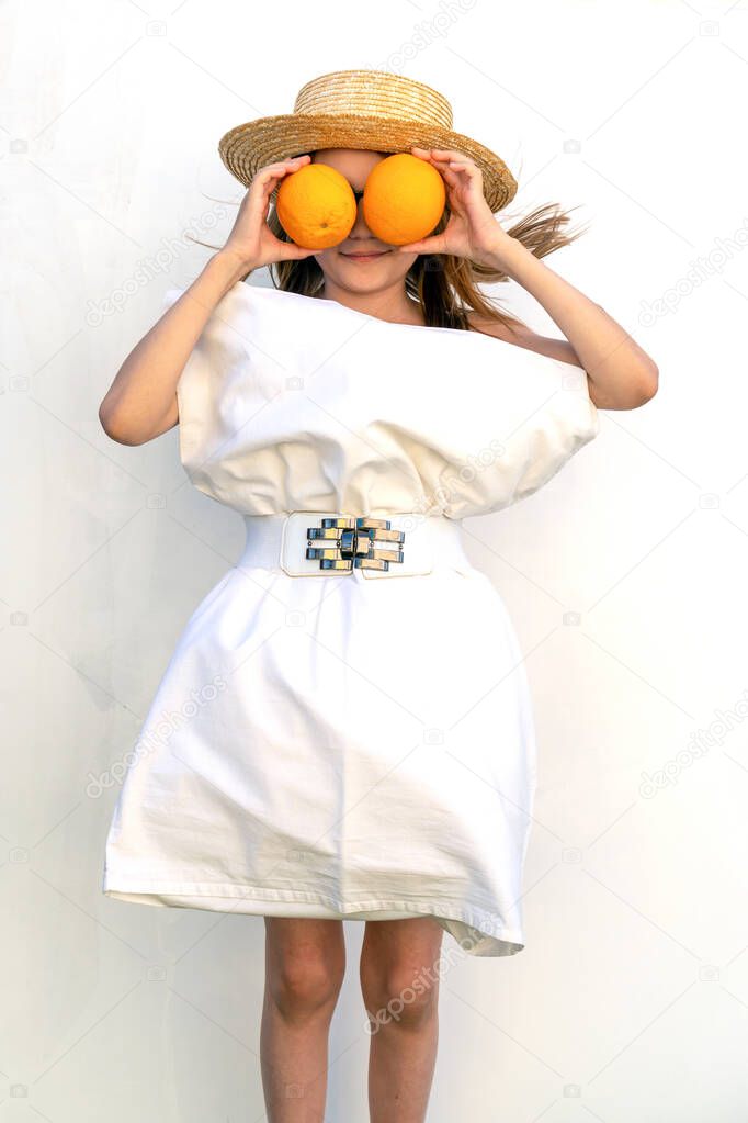 Orange A girl on a white background, wearing a white pillow instead of a dress and a fashionable hat. Teen girl has fun quarantine and holds a fashion show in style pillow challenge.