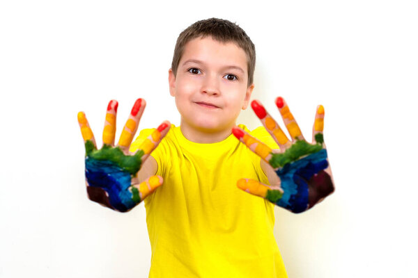 Portrait of a happy and smiling boy with multi-colored hands. Rainbow on the hands. Space for text,