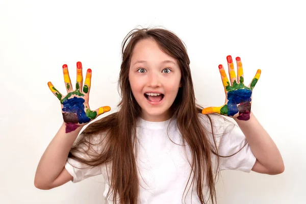 Retrato de una chica feliz y sonriente con palmas multicolores. La chica se ve sorprendida y entusiasta, sus ojos bien abiertos. Arco iris en las manos. Manos de colores — Foto de Stock