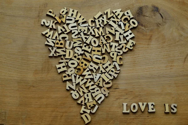 Corazón de letras de madera sobre un fondo de madera — Foto de Stock