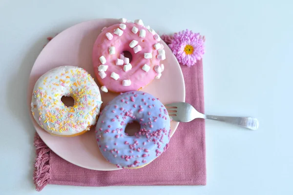 Разноцветные пончики на розовой тарелке — стоковое фото
