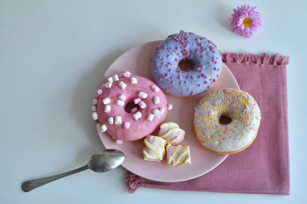 Багатокольорові пончики на рожевій тарілці. — стокове фото
