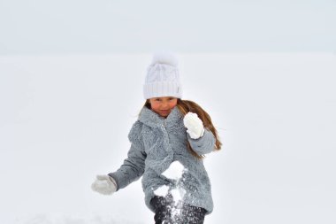 Kış yürüyüşü yapan mutlu bir kız çocuğu. Küçük çocuk kış tatilinde oynuyor. Kış gölündeki kız.