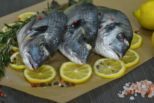 Peixe cru com ervas aromáticas, especiarias, sal e fatias de lima. Dorado cru em fundo escuro. Alimentos saudáveis, cozinhar, dieta, conceito de nutrição . — Fotografia de Stock