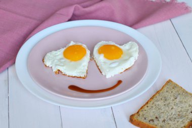 Tahta masada sağlıklı kahvaltı için pembe tabakta iki kızarmış yumurta. en üstteki görünüm