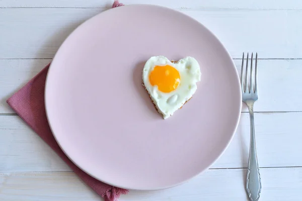 Two fried eggs on pink plate for healthy breakfast on wooden table. top view