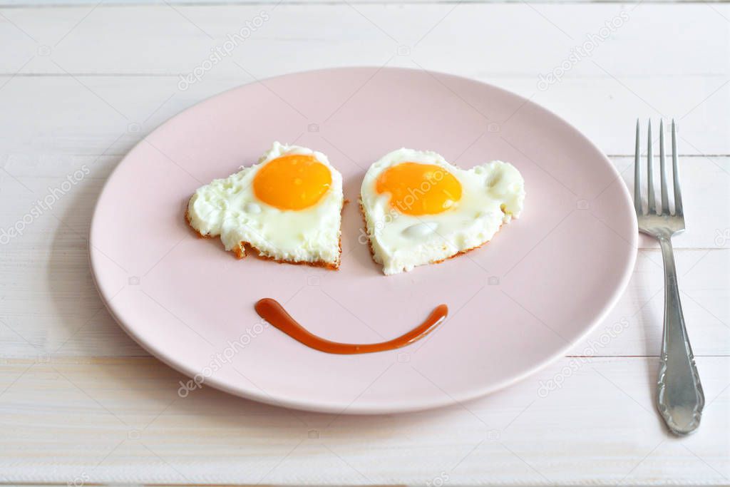 Two fried eggs on pink plate for healthy breakfast on wooden table. top view