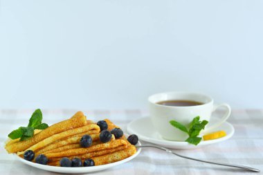 a stack of pancakes with berriesand cup of tea.Pancake week: thin pancakes with butter and tea on white table.french crepes .Delicious breakfast.Selective focus.