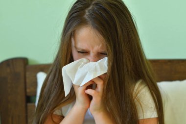 Küçük kız burnunu siliyor. Peçeteli hasta çocuk. Alerjik çocuk, grip mevsimi. Soğuk Rhinitis 'li çocuk, soğuk sümük burunlu olsun. virüs ve enfeksiyon