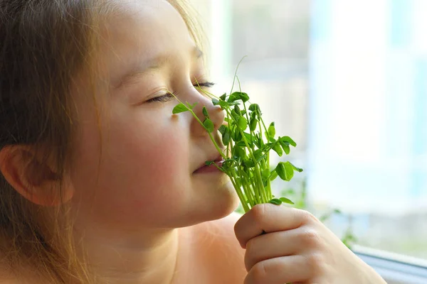 Happy girl eats pea microgreen .vegeterian concept.good appetite. spring avitaminosis.sprout vegetables germinated from high quality organic plant seed on linen mat.superfood.selective focus.
