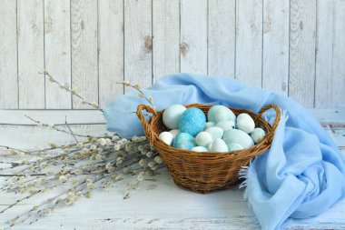 Hasır bir sepette mavi Paskalya yumurtaları ve arka planda söğüt çiçekleri. Doğal olarak mermer taşlı amber çiçeğiyle boyanmış yumurtalar. Eko boya. Mutlu Paskalya kartları. Seçmeli odaklanma..