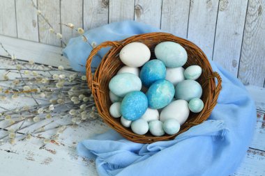 Hasır bir sepette mavi Paskalya yumurtaları ve arka planda söğüt çiçekleri. Doğal olarak mermer taşlı amber çiçeğiyle boyanmış yumurtalar. Eko boya. Mutlu Paskalya kartları. Seçmeli odaklanma..