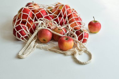 Kırmızı elmalarla dolu bir tekstil çantası. - Sıfır yiyecek alışverişi. Beyaz arka planda eko doğal torbalar. Çevre dostu kavram. Plastiksiz minimalist yaşam tarzı. Yeniden kullan, azalt, geri dönüştür. Plastiğe hayır de.