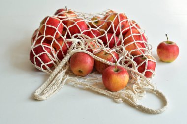 Kırmızı elmalarla dolu bir tekstil çantası. - Sıfır yiyecek alışverişi. Beyaz arka planda eko doğal torbalar. Çevre dostu kavram. Plastiksiz minimalist yaşam tarzı. Yeniden kullan, azalt, geri dönüştür. Plastiğe hayır de.